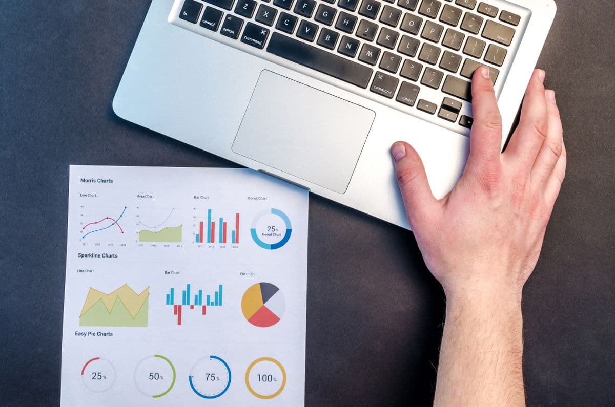 Notebook aberto ao lado de relatório impresso com gráficos financeiros